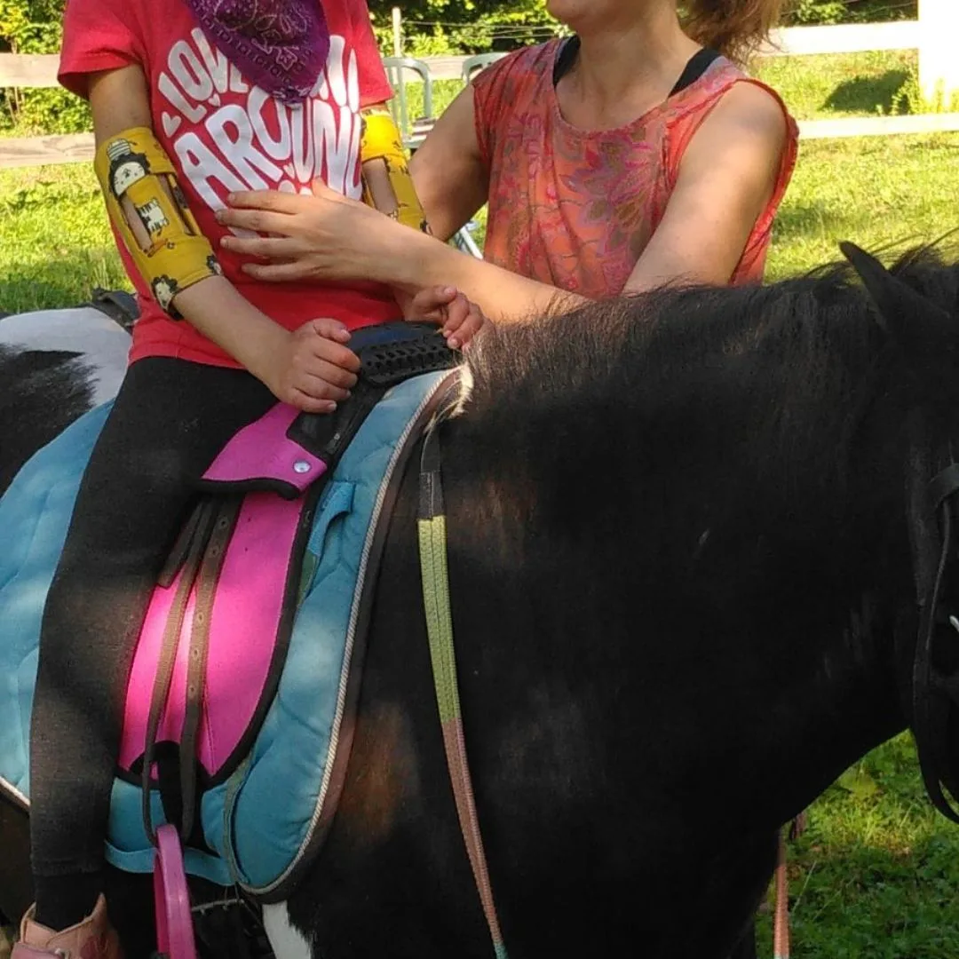 Séance d’hippothérapie en Ariège, enfant sur un poney accompagné par la kinésithérapeute